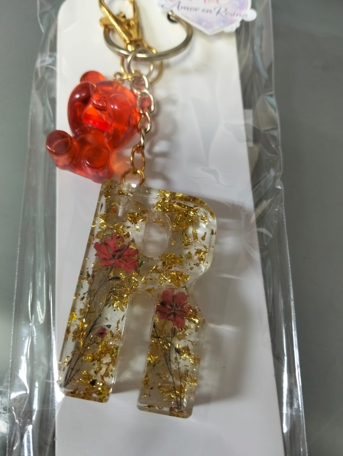 Llavero de resina en letra R, con detalles dorados y flores rojas